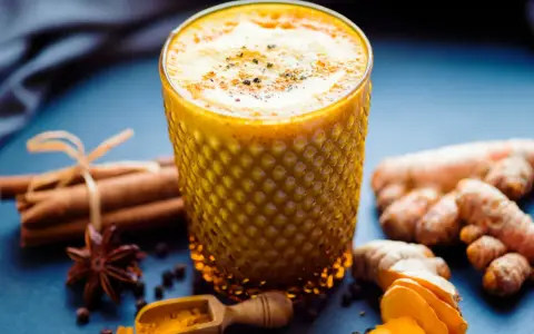 Ein Glas goldene Milch mit Kurkuma, Ingwer, Zimt und Sternanis. So wird goldene Milch gemacht.