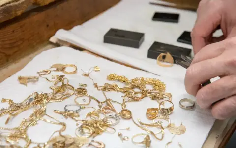 Mani esperte valutano gioielli d'oro, anelli e collane, un modo pratico per imparare come riconoscere l'oro.