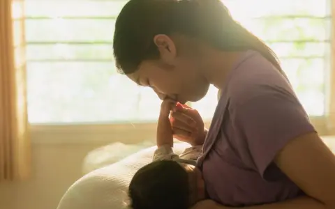 Dolce momento tra madre e neonato. La mamma bacia la manina del piccolo, attenta ai suoi segnali fame.