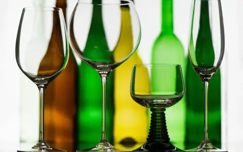 Leere Weingläser stehen vor bunten Flaschen. Perfekt, wenn man Wein kalt trinkt.