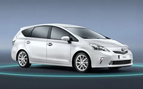 Biały Toyota Prius+ na tle niebieskim. To auto hybrydowe, które oferuje przestronne wnętrze, idealne dla rodziny. Ile miejsc ma ten model?