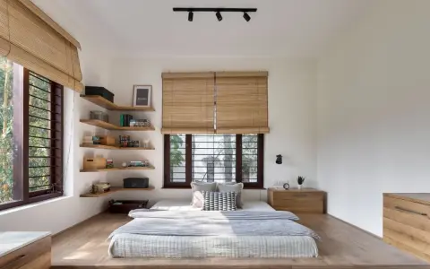 Habitación con cama baja, estanterías de madera y persianas de bambú. Un ejemplo de estilos de habitaciones minimalistas y acogedoras.