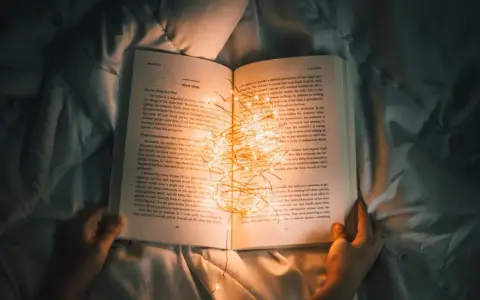 Książka z zapaloną girlandą światełek, idealna na życzenia dla nastolatka.