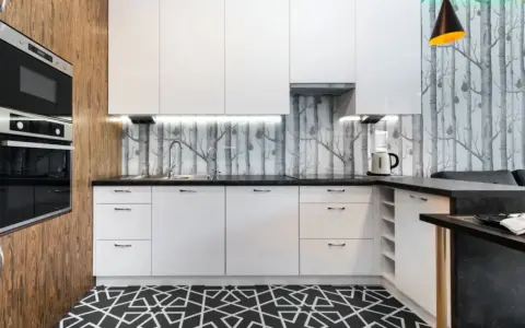 Cocinas modernas con papel pintado de árboles, gabinetes blancos y suelo geométrico.