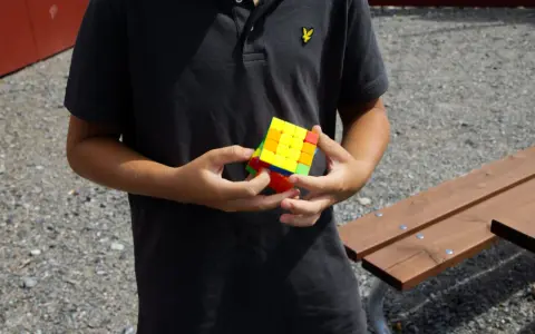 Ungdom med en färgglad Rubiks kub i händerna, redo för rubiks kub speed.