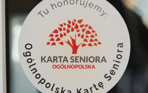 Naklejka z napisem "Tu honorujemy: KARTA SENIORA OGÓLNOPOLSKA" i drzewem. Dostępne zniżki dla posiadaczy ogólnopolskiej karty seniora.