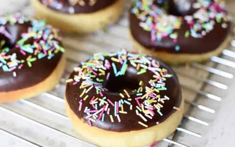 Färska, hembakade donuts med chokladglasyr och färgglatt strössel ligger på ett galler. Perfekt för att baka donuts!