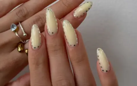 Modne paznokcie wzory galeria: kremowe migdałki z błyszczącymi kropkami. Delikatny manicure, który przyciąga wzrok.