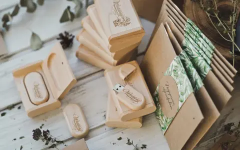 Drewniane pendrive'y z grawerem "Wedding" i koperty z motywem roślinnym. Personalizowane upominki dla gości od pary młodej to klucz do sukcesu.