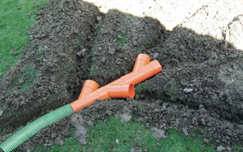 Tubi arancioni a Y e un tubo verde in una trincea: il sistema per capire come drenare il terreno.