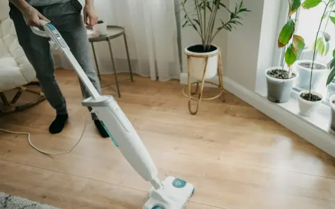 Osoba sprząta panele winylowe za pomocą mopa parowego.
