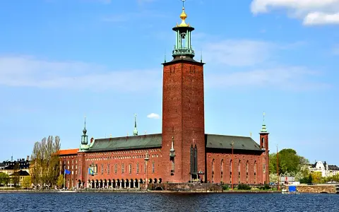 Stockholms stadshus reser sig stolt vid vattnet, dess ikoniska torn dominerar horisonten.