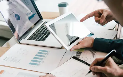 Analyse de rapports financiers sur tablette et ordinateur portable, illustrant la gestion administrative d'une entreprise.