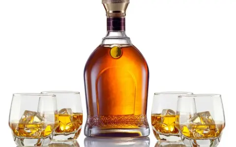 Elegancka butelka whisky i cztery szklanki z lodem. Czy to single malt czy blended, każdy znajdzie coś dla siebie.