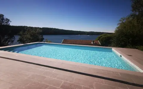 En lyxig pool med klarblått vatten och en fantastisk utsikt över en sjö. En dröm för många, men vad är bygga pool kostnad?