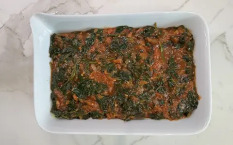 Lasaña de espinacas en salsa de tomate en un plato blanco.