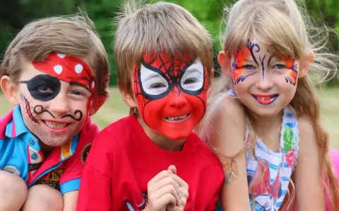 Niños con pintacaras de pirata, Spider-Man y mariposa sonriendo.