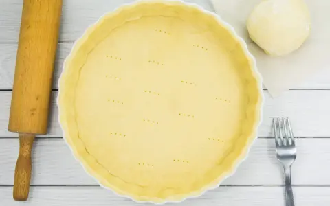 Pâte à tarte à la casserole prête à être garnie, avec une boule de pâte, un rouleau et une fourchette.