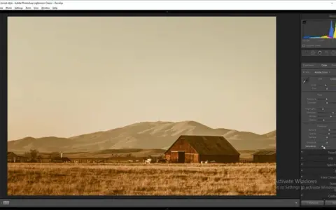 Paisaje rural con granero y montañas, con un filtro sepia aplicado en Photoshop para un estilo vintage.