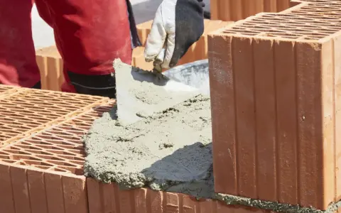 Budowanie muru z pustaków ceramicznych, nakładanie zaprawy. Właśnie tak jak zrobic cement do budowy.