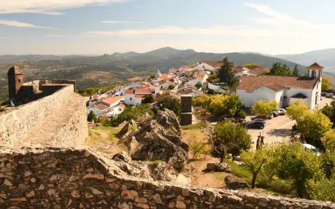 Blick auf das malerische Dorf Portalegre mit seinen weißen Häusern und roten Dächern, umgeben von einer alten Steinmauer und bergiger Landschaft.