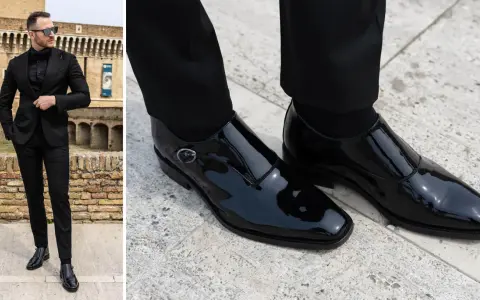 Uomo con vestito nero e camicia abbinata, indossa eleganti scarpe da abbinare in vernice nera.
