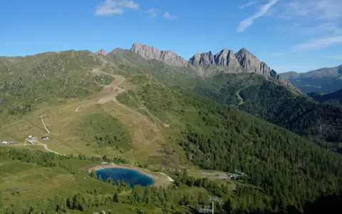 Panorami alpini con sentieri per passeggiate facili vicino a Trento, un lago azzurro e cime rocciose.