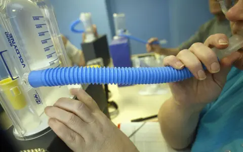Person nutzt ein Spirometer für einen Lungenfunktionstest. Der Asthmaspray ist nicht sichtbar, aber das Gerät hilft bei der Diagnose.