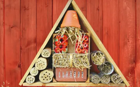 Ein Insektenhotel mit verschiedenen Materialien wie Holzscheiten, Stroh und Tonscherben. Hier finden Insekten ein Zuhause und Brutstätte.