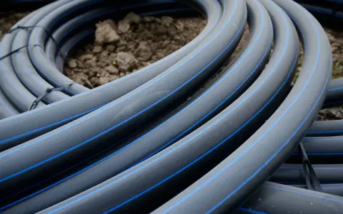 Coiled black hdpe plastic pipes with blue stripes, ready for installation.