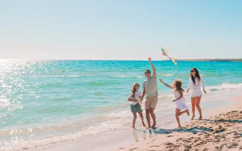 Rodzina puszcza latawiec na piaszczystej plaży. Piękne kąpieliska nad Bałtykiem zachęcają do zabawy.