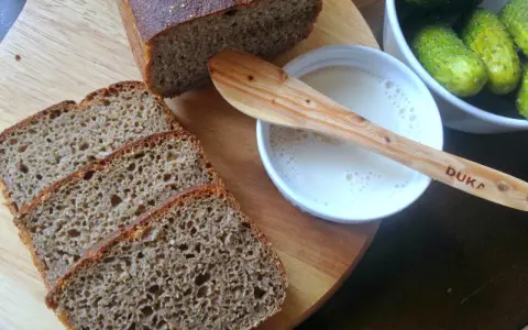 Kromki pysznego chleba z mąki razowej, obok miseczka z mlekiem i ogórki kiszone. Idealny zestaw na śniadanie.