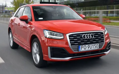 Czerwone Audi Q2 w ruchu miejskim. Choć jego design jest atrakcyjny, warto rozważyć potencjalne wady, takie jak ograniczona przestrzeń bagażowa.