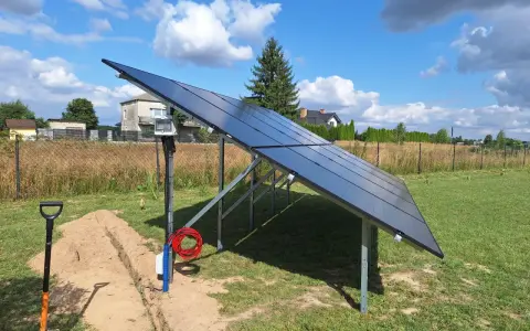 Nowa instalacja fotowoltaiczna w granicy działki, gotowa do podłączenia. Obok koparka i materiały.