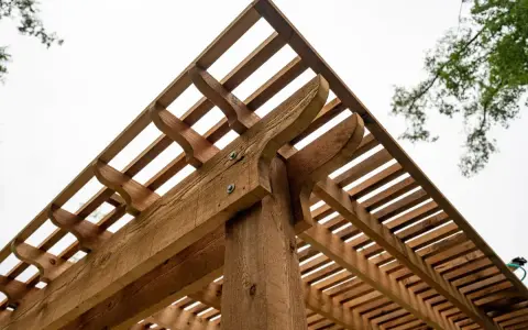 Drewniana pergola z ozdobnymi wspornikami. Dowiedz się, jak wysuszyć mokre drewno konstrukcyjne, aby służyło latami.