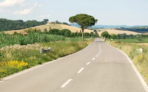 Eine Straße schlängelt sich durch die toskanische Landschaft. Perfekt, um die nächste **europa reise planen** und die Schönheit Italiens zu entdecken.