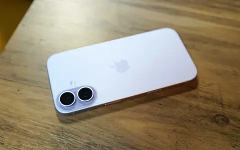 A light purple iPhone with a dual-camera system lies on a wooden surface.