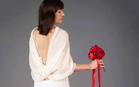 Donna con un bouquet di rose rosse, indossa un morbido indumento tipicamente femminile indossato per proteggere le spalle.