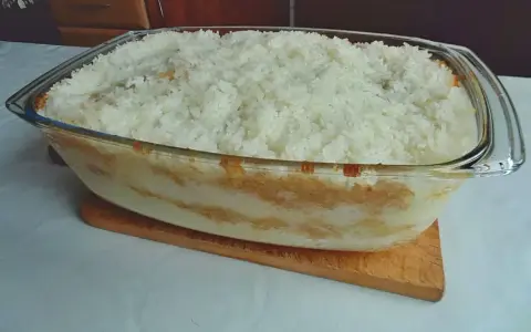 Pyszny ryż z jabłkami w szklanym naczyniu, gotowy do pieczenia. Warstwy jabłek i ryżu kuszą aromatem.