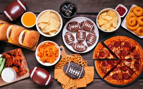 Perfekte Super Bowl Snacks: Pizza, Chicken Wings, Burger, Chips, Brownies in Football-Form und mehr.