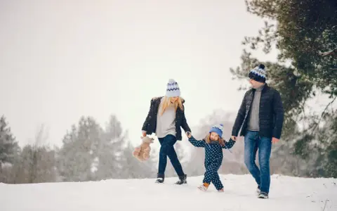 Famiglia felice in vacanze montagna bambini, camminano nella neve con cappelli coordinati.