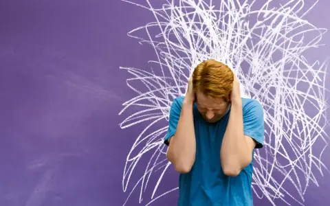 Junge mit roten Haaren hält sich die Ohren zu, vor chaotischer Kreidezeichnung. Ein Bild für die Herausforderungen von Kindern mit ADHS und Distanzlosigkeit.