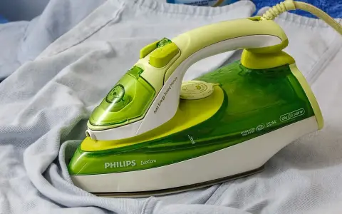 Ferro da stiro Philips EcoCare verde e giallo su un capo di abbigliamento. Non si vede a quanti gradi arriva il ferro da stiro.