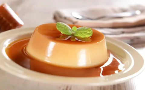 Un délicieux panna cotta caramel, nappé de sauce et garni d'une feuille de menthe. Un dessert onctueux et gourmand.