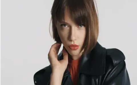 Mujer con cortes bob modernos, mirada intensa y labios rojos, luciendo una chaqueta de cuero negra.