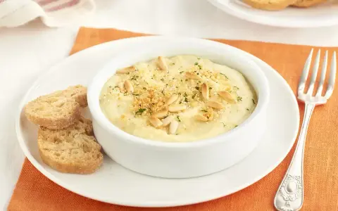 Deliciosa brandada de merluza cremosa, gratinada con piñones y pan rallado, servida con tostas.