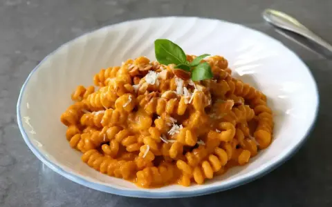 Pyszny makaron fusilli w kremowym sosie pomidorowym, posypany parmezanem i orzeszkami. Idealny makaron na obiad.