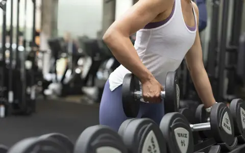 En person lyfter en hantel, tränar sina typ 1 muskelfibrer i gymmet.