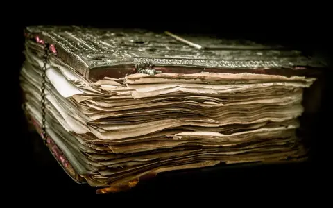 Un antico libro rilegato in metallo, con pagine ingiallite e consumate, evoca il mistero del manoscritto di Voynich.