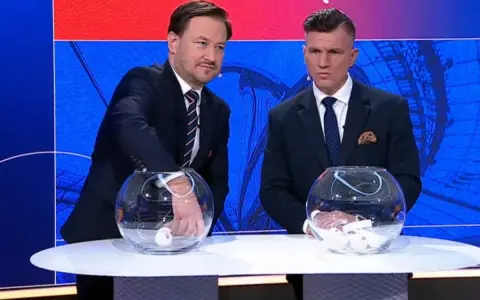 Dwóch mężczyzn w garniturach losuje piłki z kul. Kto wygrał Puchar Polski w piłce nożnej?